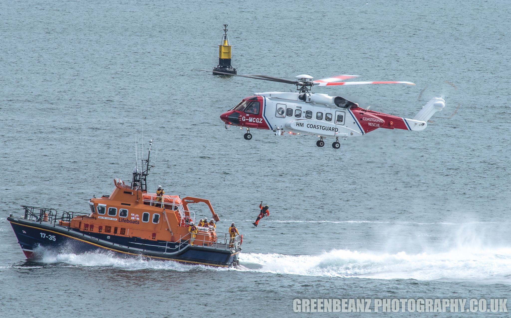 Cropped telephoto photograph of a coastguard helicopter and RNLI boat